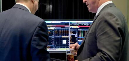 Investors talking in front of computer screen showing stock market trends - USA