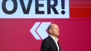 German Chancellor and member of the Olaf Scholz speaks in front of a sign reading 'OVER!' during a SPD Citizens' Dialogue at the Career Campus in Hannover, Germany, Thursday, Feb. 20, 2025. (Julian Stratenschulte/dpa via AP)