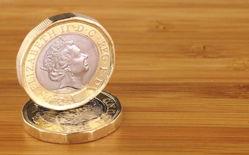 Two new English one pound coins on a wooden background