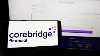 Person holding mobile phone with logo of American company Corebridge Financial Inc. on screen in front of web page. Focus on phone display.