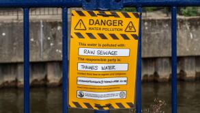 Protest sign reading Danger water pollution, this water is polluted with raw sewage. The responsible party is Thames Water. River Wey, Guildford, UK