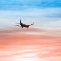 Large plane flies in the evening sunset sky, dramatic painted sky and airplane silhouette with clouds over Lisbon in Portugal