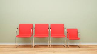Three larger chairs and one smaller chair in a row in an empty room - difference concept