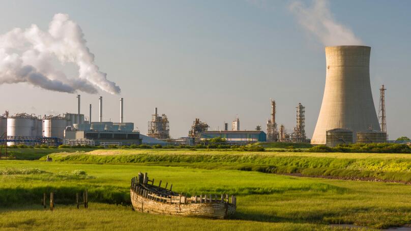 A chemical plant on the bank of the Humber estuary with derelict boat beached in the mud bank.