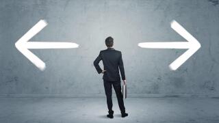 A businessman in doubt, having to shoose between two different choices indicated by arrows pointing in opposite direction concept