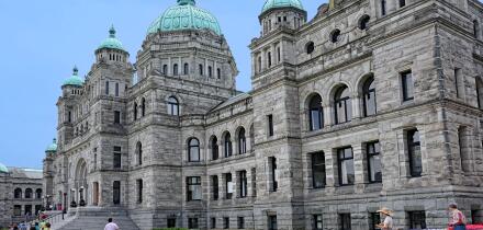 Victoria, BC, Canada -  Visitors walk past the front of the baroque style provincial parliament building of British Columbia, in the ca