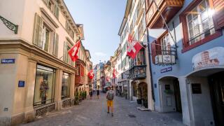 Tourist in Augustinergasse, alleyway with historic houses and Swiss flags in the old town, Zurich, Switzerland