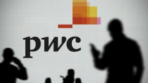The PWC logo is seen on an LED screen in the background while a silhouetted person uses a smartphone in the foreground (Editorial use only)