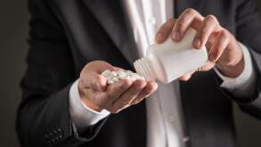 Pharmaceutical representative, consultant or head director or manager of medicine company with white tablets. Man in a suit pouring spilling pills.