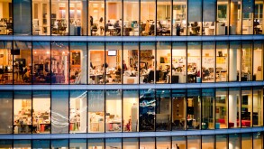 London, UK - February 2013: people work in a modern office building at dusk.