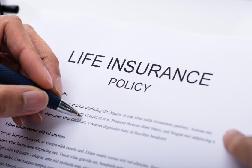 Close-up Of A Person's Hand Filling Life Insurance Policy Form