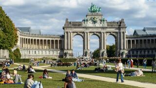 People seated in the Cinquantenaire Park, enjoying the sunshine at the end of September.| Les gens sont assis dans le parc du cinquantenaire et profit