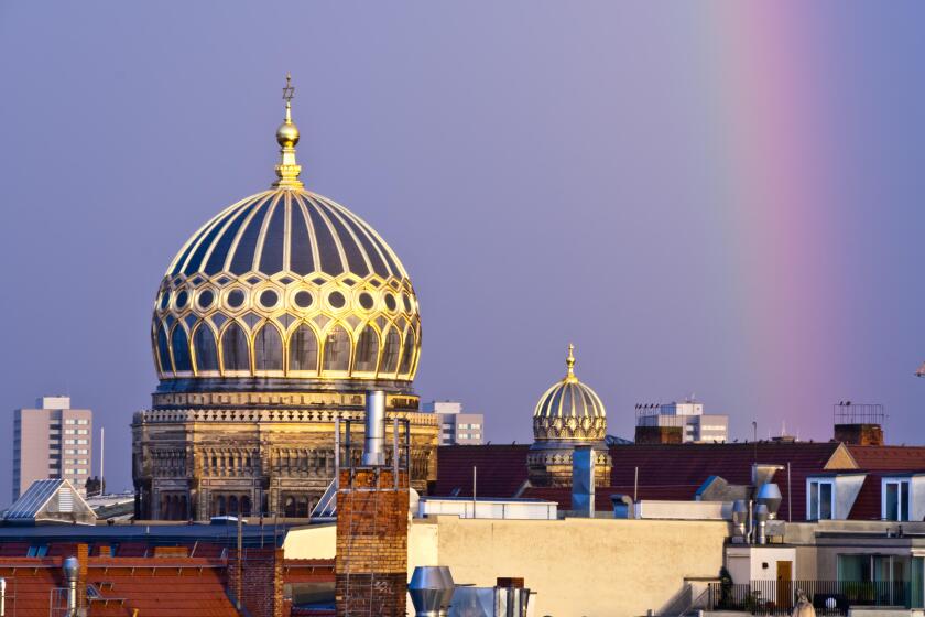 Berlin cathedral and synagogue domes in Berlin, Germany adorned with a rainbow after a summer storm.