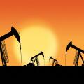 Rows of oil pumpjacks silhouette against a sunset sky with copy space. Oil and gas energy exploration.