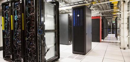 Racks of servers aligned in rows in a large computer server farm.