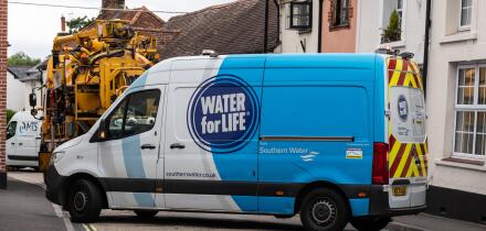 Southern Water company van and other vehicles parked blocking road while fixing a burst water main, Overton, Hampshire, England, UK