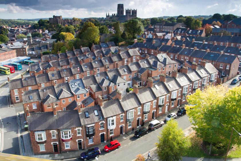A view from above looking down onto rows of tightly packed terraced houses on the city streets of Durham, UK.