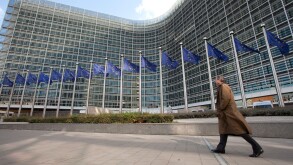 A man walks next to the european flags outside the Berlaymont building, the European Commission headquarters in Brussels