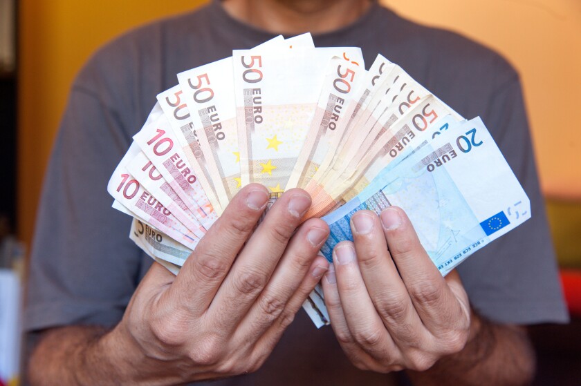 Close up of hands holding wad of Euro banknotes