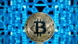 Standing golden bitcoin crypto currency blockchain coin against a blue reflective circuit board background