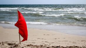 Flags on the beach indicate dangers like jellyfish, undercurrent and other dangers. Image shot 12/2019. Exact date unknown.