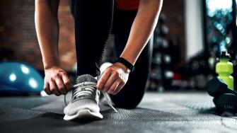 Runner, hands and tying shoes for training, fitness and exercise or running with sneakers, fashion and getting ready. Person or athlete with laces and