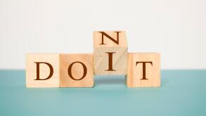 Hand flipping one wooden cube to change the word Don't for Do it on neutral background