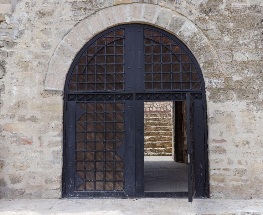 Black iron open gate in a stone wall, entrance into a medieval fortress