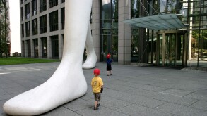 kids impressed by big foot Walking Man in front of Muenchener Rueckversicherung Munich Re Bavaria Germany