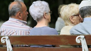 Elderly back sitting on a bench.