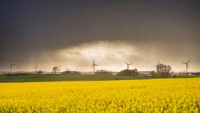 Landscape with wind turbines and fields of flowering rape seed and storm clouds behind. Osterlen, Skane, Sweden. Scandinavia.