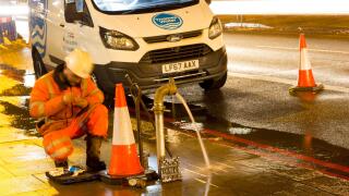 watermain burst repaired by Thames water engineer at road side, England