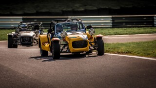 2 Caterham Seven sports cars racing at Cadwell park race track.