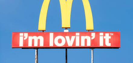 McDonald's logo arches sign and I'm Lovin' It slogan against blue sky with copy space