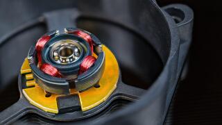 Electric motor rotor with permanent magnet, copper wire inductors and metal ball bearing. Disassembled computer fan with integrated Hall-effect sensor.