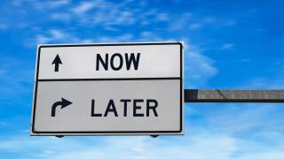Road sign with words now and later. White two street signs with arrow on metal pole. Directional road, Crossroads Road Sign, Two Arrow. Blue sky backg