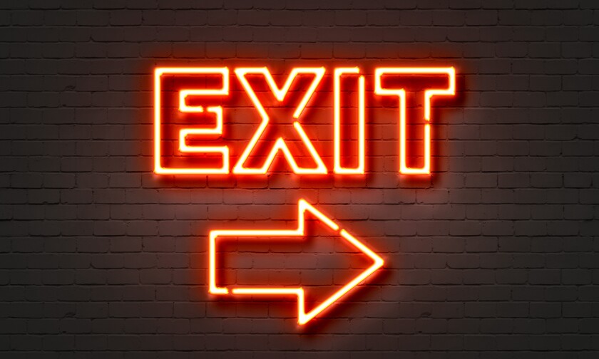 Exit neon sign on brick wall background.