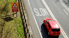 Speeding car approaching warning to slow down, on UK road