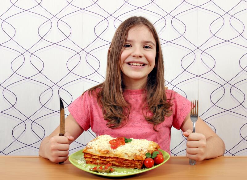 happy little girl with lasagne on table