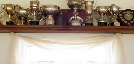 Trophies on a shelf above a list of honorary members plaque in the interior of the club house at the Mauchline lawn bowling green in Mauchline; Ayrshi