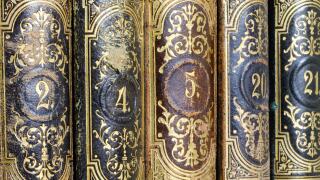 Vintage ornate book spines with intricate gold designs and numbers.