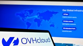 Mobile phone with logo of French cloud computing provider OVH Groupe SAS on screen in front of website. Focus on center-left of phone display.