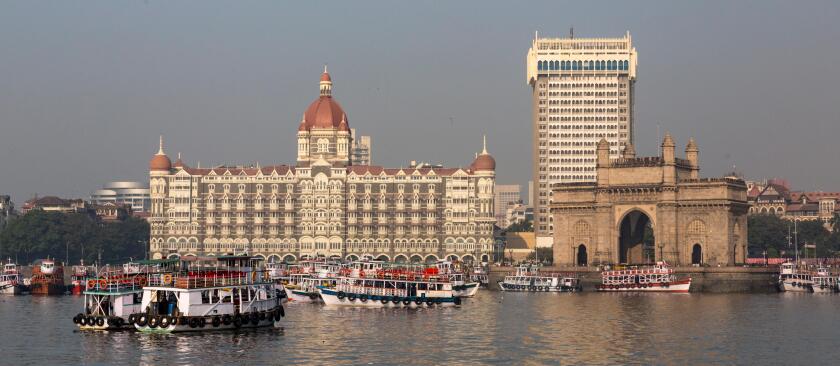 Mumbai waterfront from harbor with skyline, excursion boats, Gateway of India arch and Taj Mahal Palace Hotel