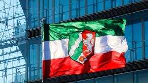 NRW North Rhine-Westphalia flag on flagpole blowing in the wind in front of the facade of the city gate, Dusseldorf, North Rhine-Westphalia, Germany