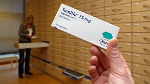 Hand holding Tamiflu medicine box in pharmacy Roche bird flu
