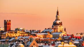 Katarina Church and the roof tops of the district of Sodermalm, Stockholm, at sunset, clear sky, winter, snow. Pink orange colors.