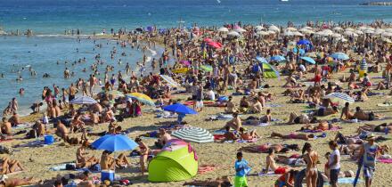 Crowded Barceloneta beach, hot summer day in Barcelona Spain.