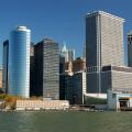 Modern skyscrapers line the waterfront in Lower Manhattan?s Financial District, New York City, with clear blue skies and calm water below