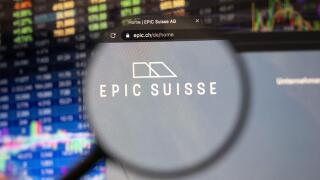 Epic Suisse company logo on a website with blurry stock market developments in the background, seen on a computer screen through a magnifying glass