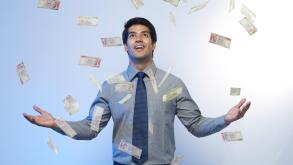 Money falling on a businessman standing with his arms outstretched